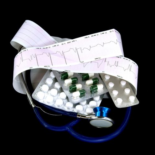 stethoscope and cardiogram with pill against black background
